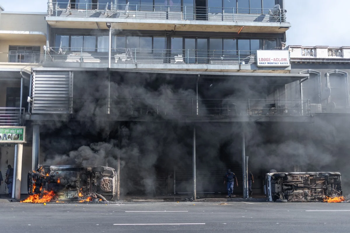 Burning and overturned vehicles outside a building during unrest in Durban, South Africa