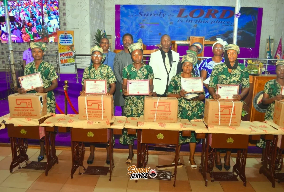 Women standing with sewing machines and certificates at an event in Akure