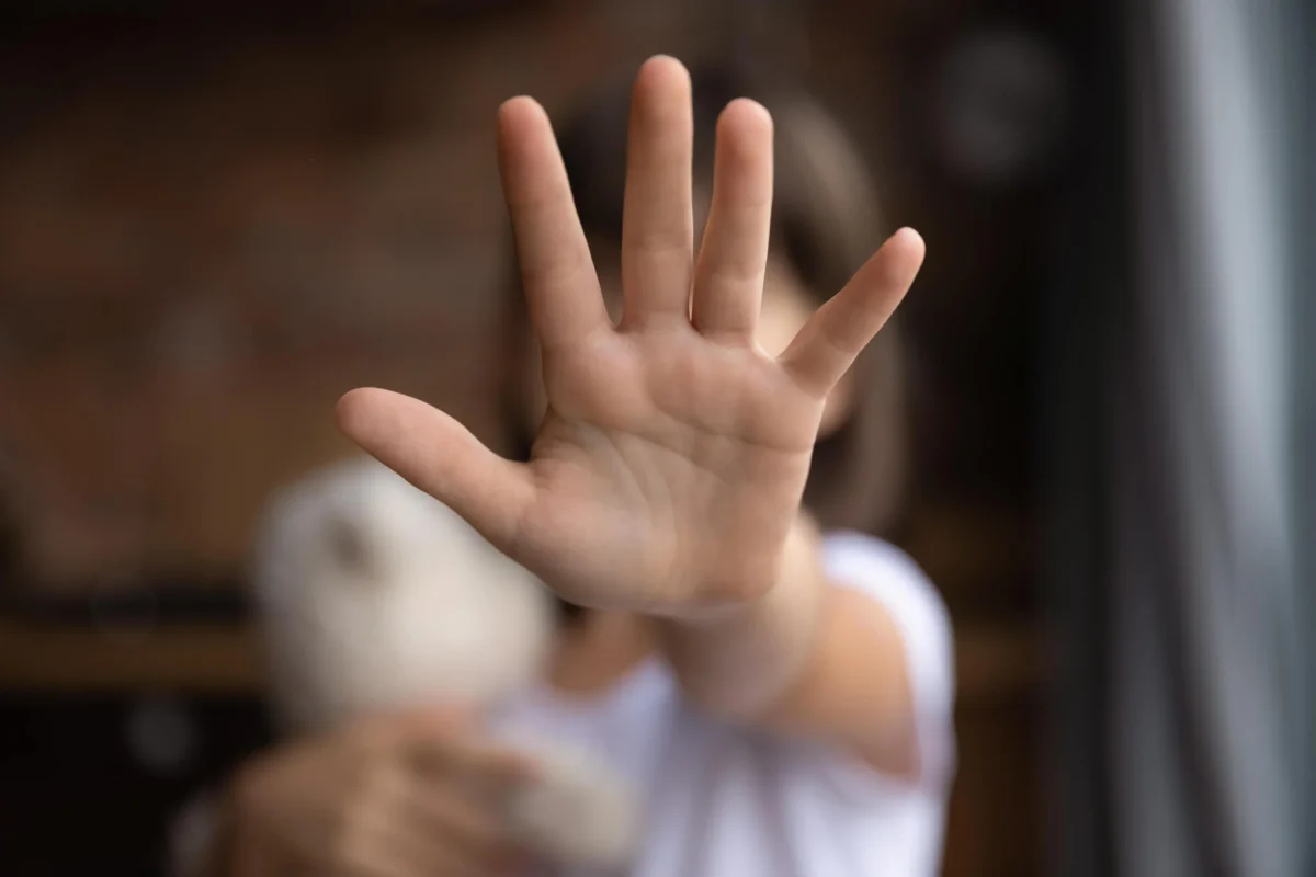 A person holding an open palm toward the camera in an image used to illustrate abuse prevention