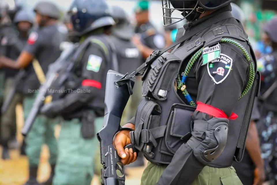 Nigeria Police officers in protective uniforms, with one officer holding a firearm in the foreground