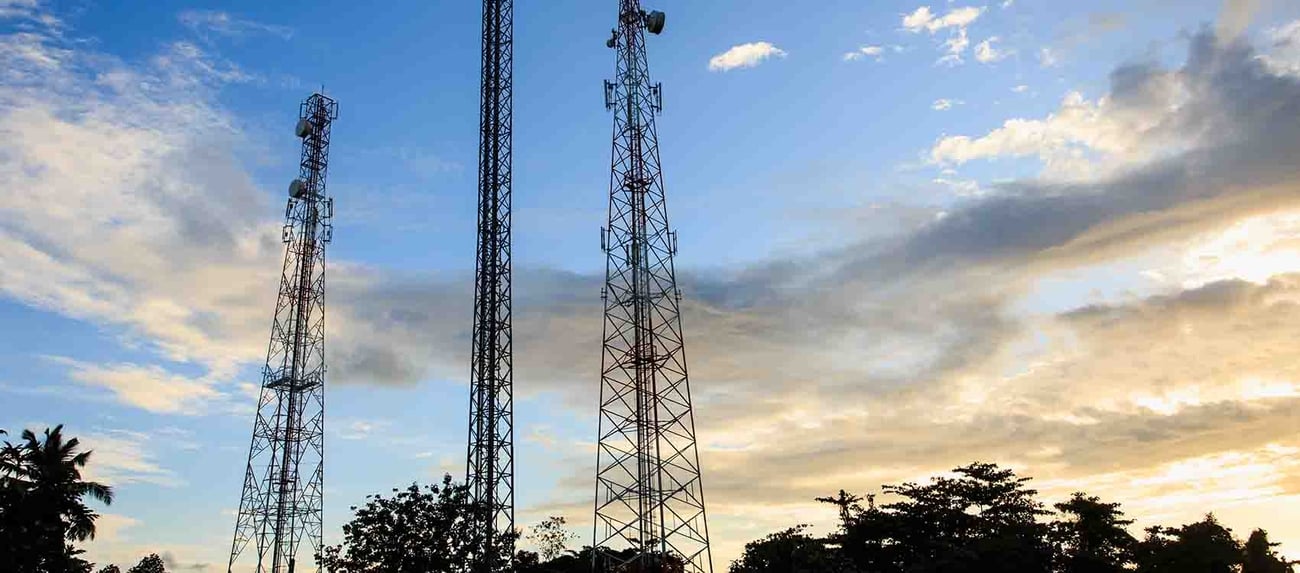 Telecommunications towers standing against a cloudy sky