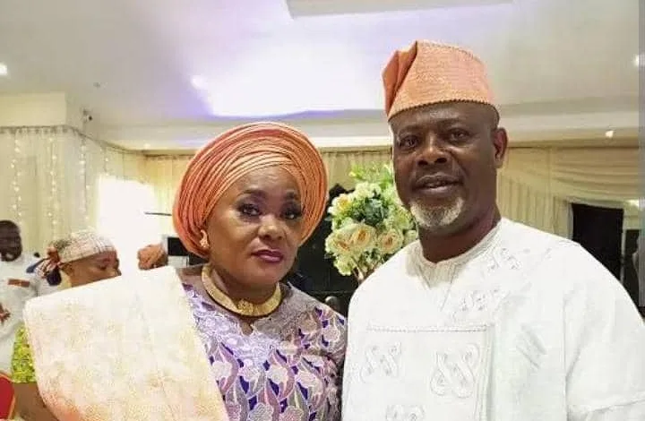 A man and woman wearing traditional attire standing together indoors