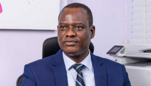 Taiwo Oyedele seated indoors wearing a blue suit and striped tie