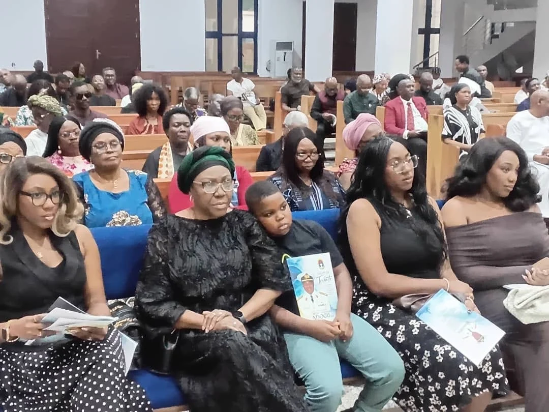Family members and other attendees seated at a tribute event for retired Commodore Bethel Adogu