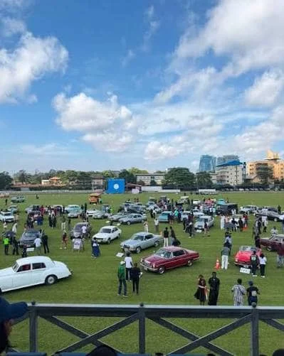 Vintage cars arranged across the grass at Lagos Polo Club while visitors walk among the vehicles