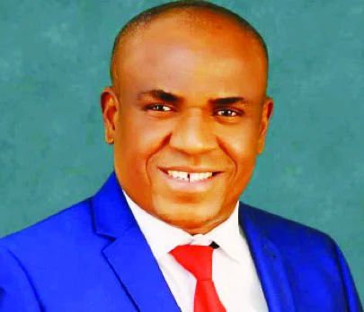 Portrait of Festus Mbisiogu wearing a blue suit and red tie