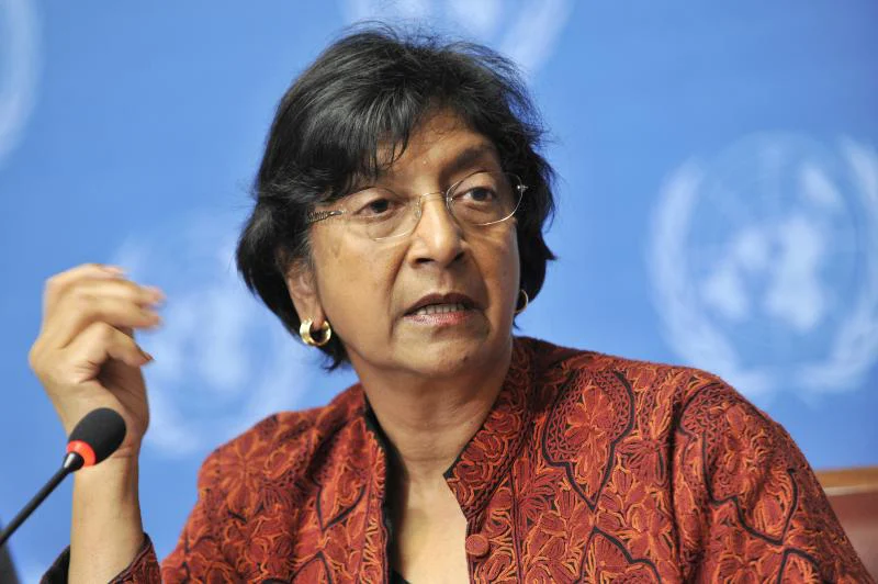 Navi Pillay speaking into a microphone against a blue backdrop