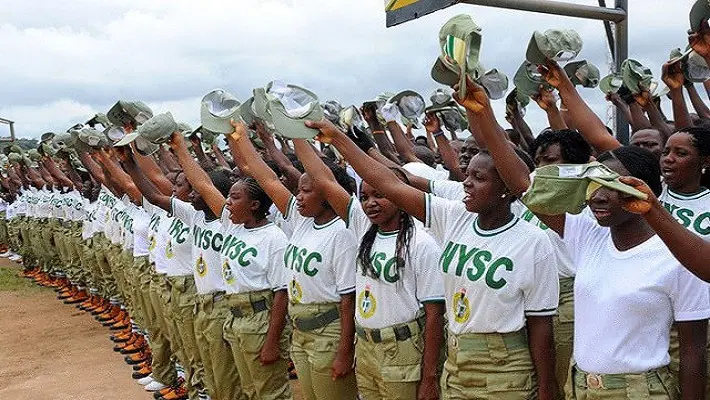 NYSC corps members standing in formation and raising their caps