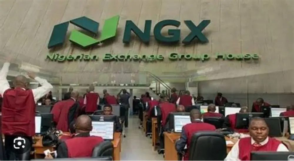 Traders seated at computer terminals on the Nigerian Exchange trading floor beneath an NGX sign