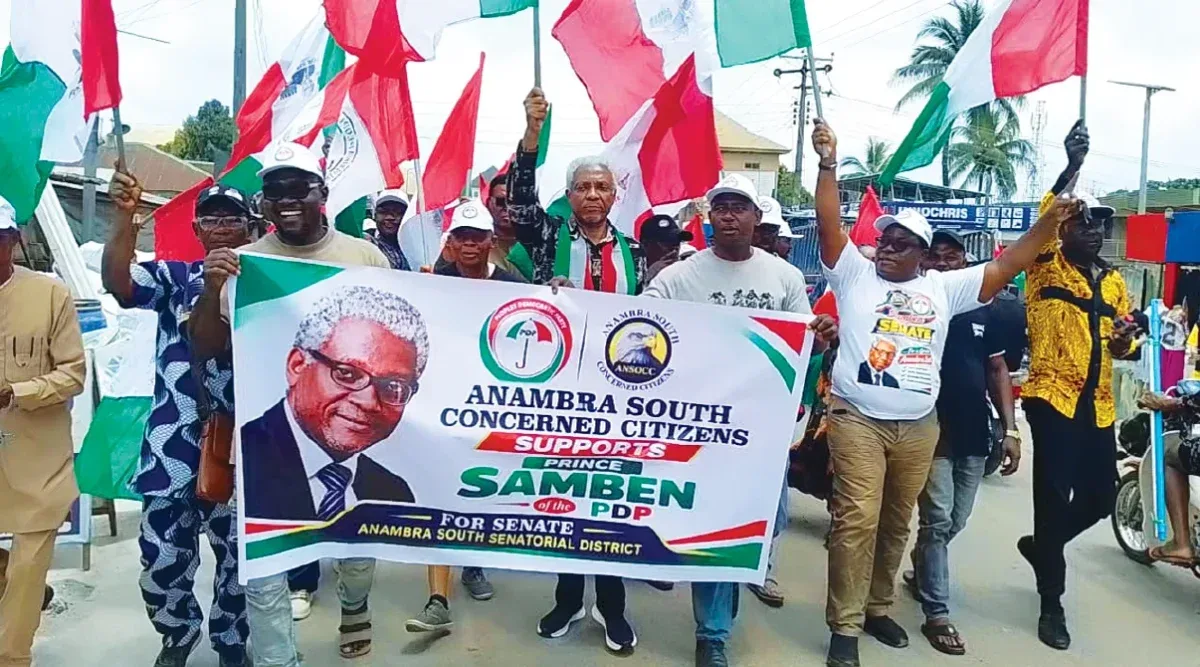 PDP supporters holding flags and a Samben Nwosu campaign banner during a road walk