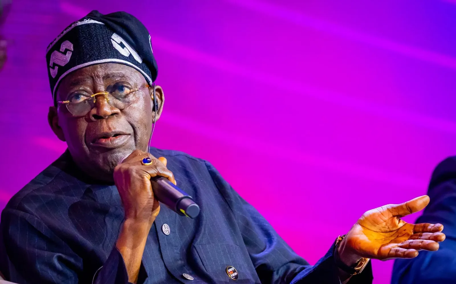 President Bola Tinubu speaking into a handheld microphone