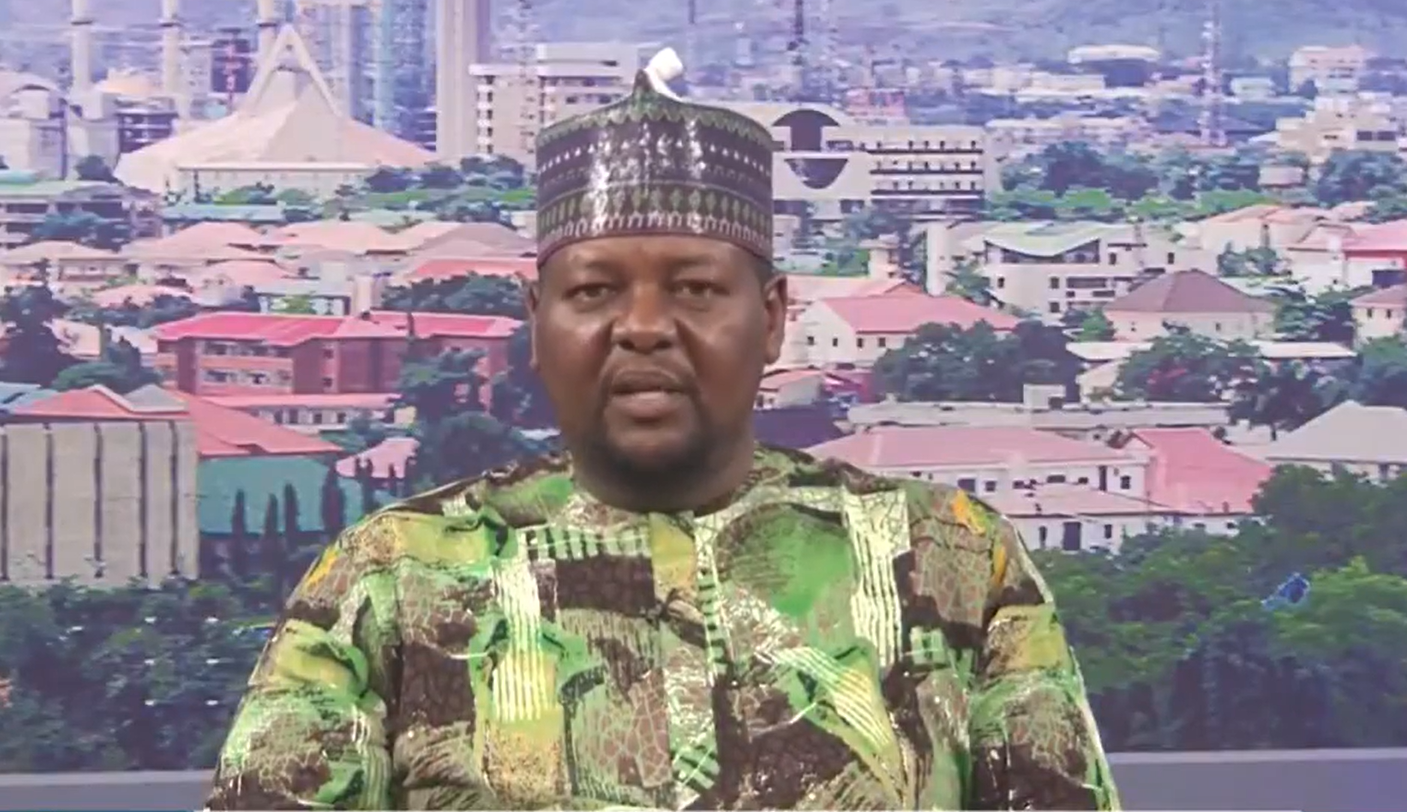 Jungudo Mohammed wearing patterned clothing and a cap during a television appearance